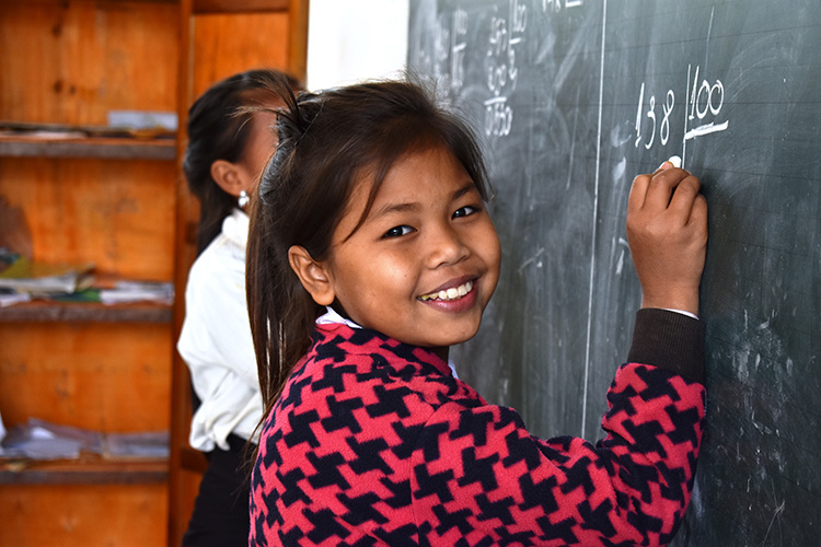  Smiling girl writing on a blackboard in a school. 