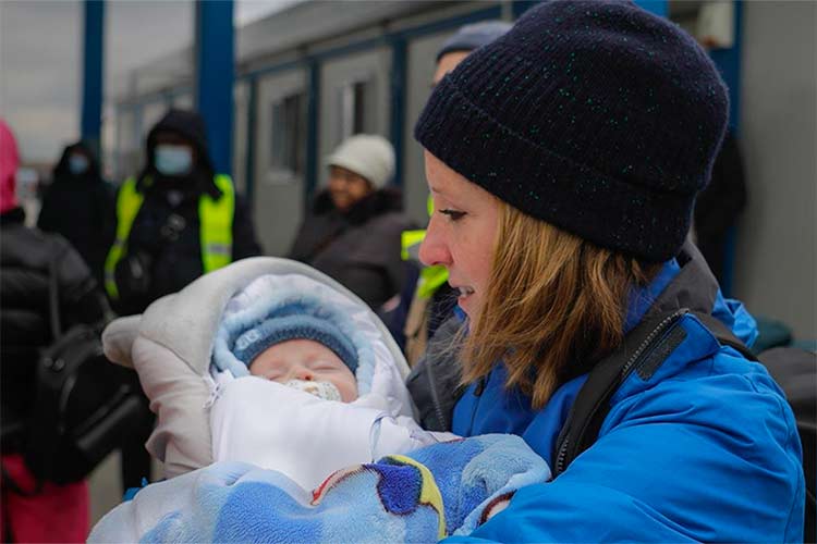 Woman, holding a baby by office buildings.