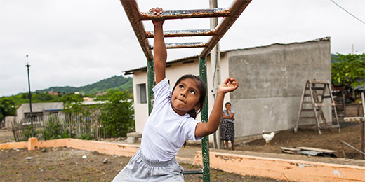 Girl plays on climbing frame in Ecuador
