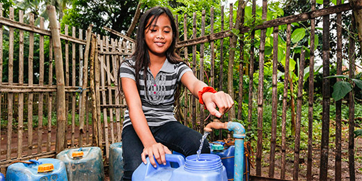Danica, 10, collects water from the new pump installed by Plan International