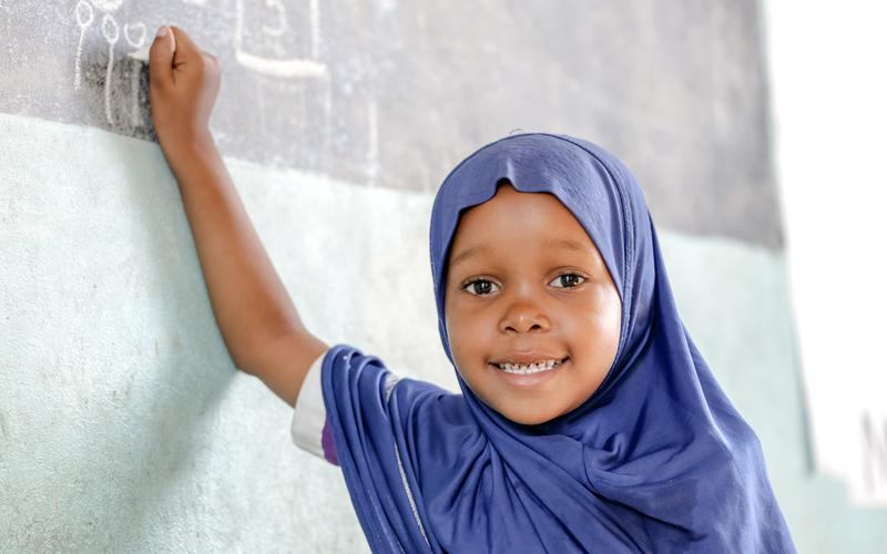 Girl writes on blackboard at ECCD centre in Kibaha district, Tanzania